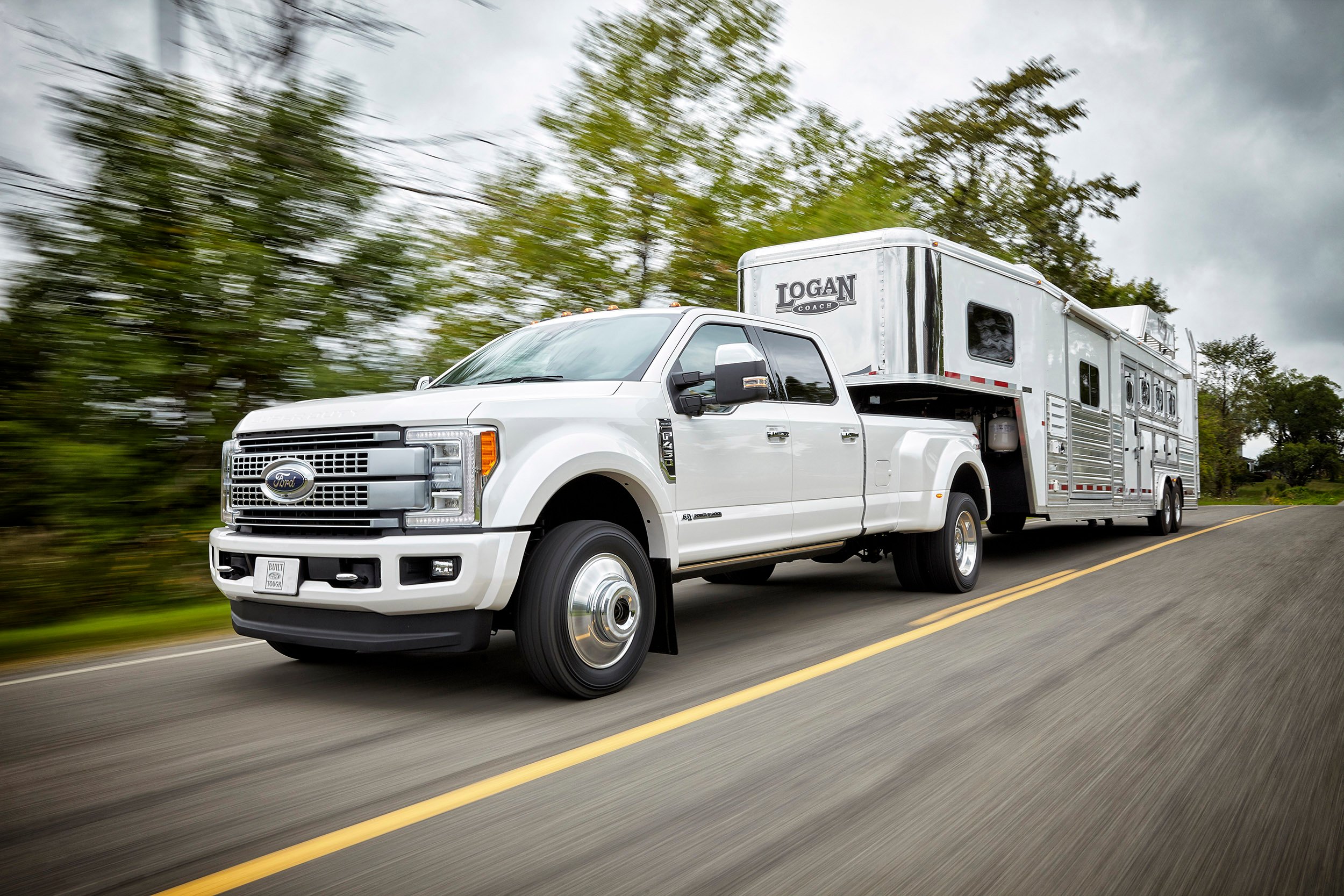 A white Ford F-450 pickup pulling a big trailer.