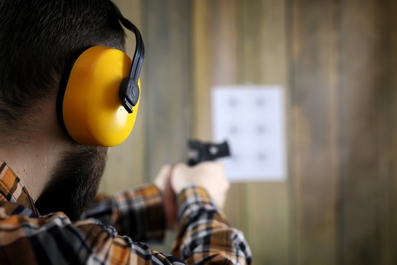 A man points a gun at a target at a shooting range.