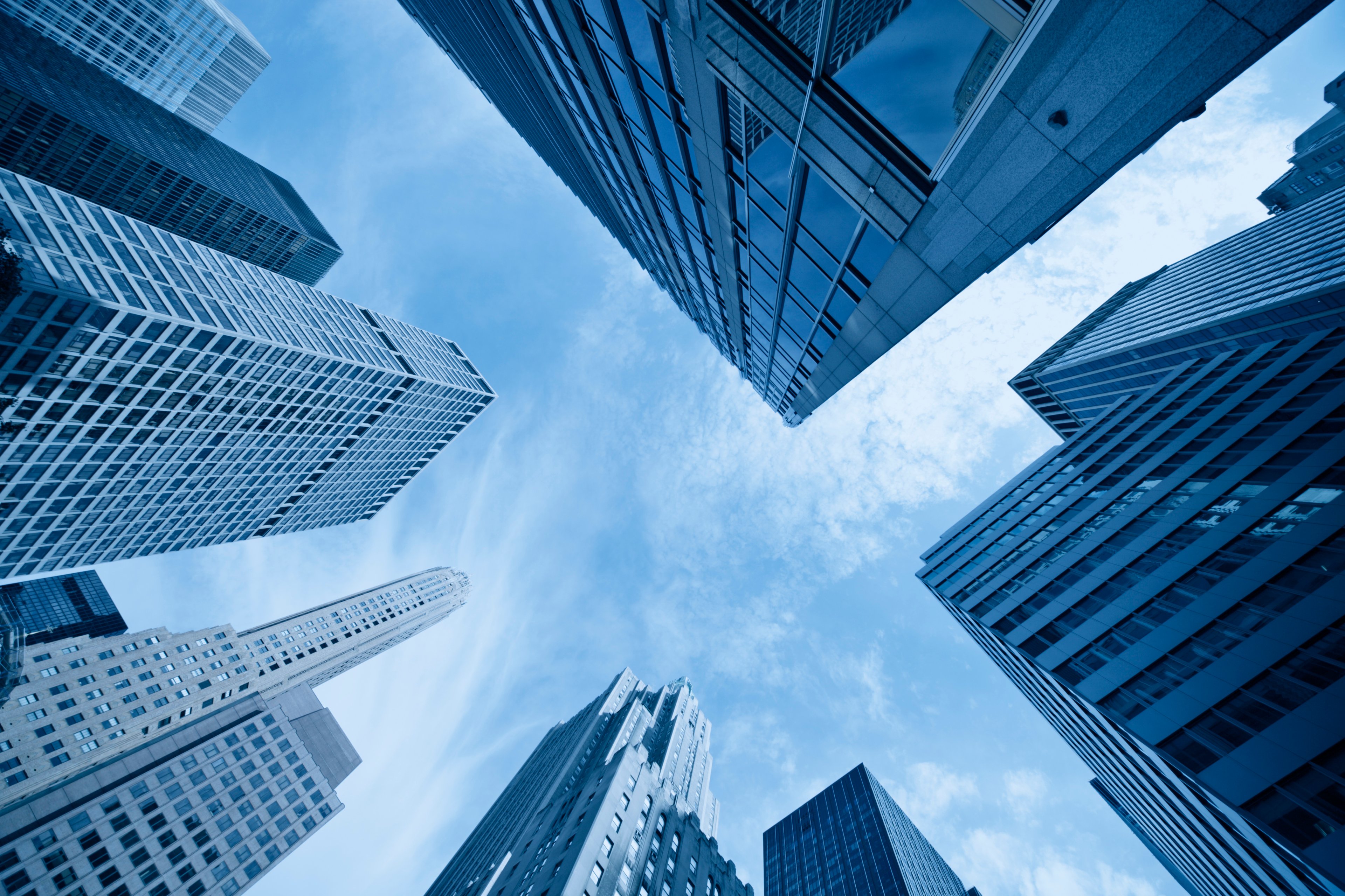 An upward-looking view of skyscrapers against a blue sky.
