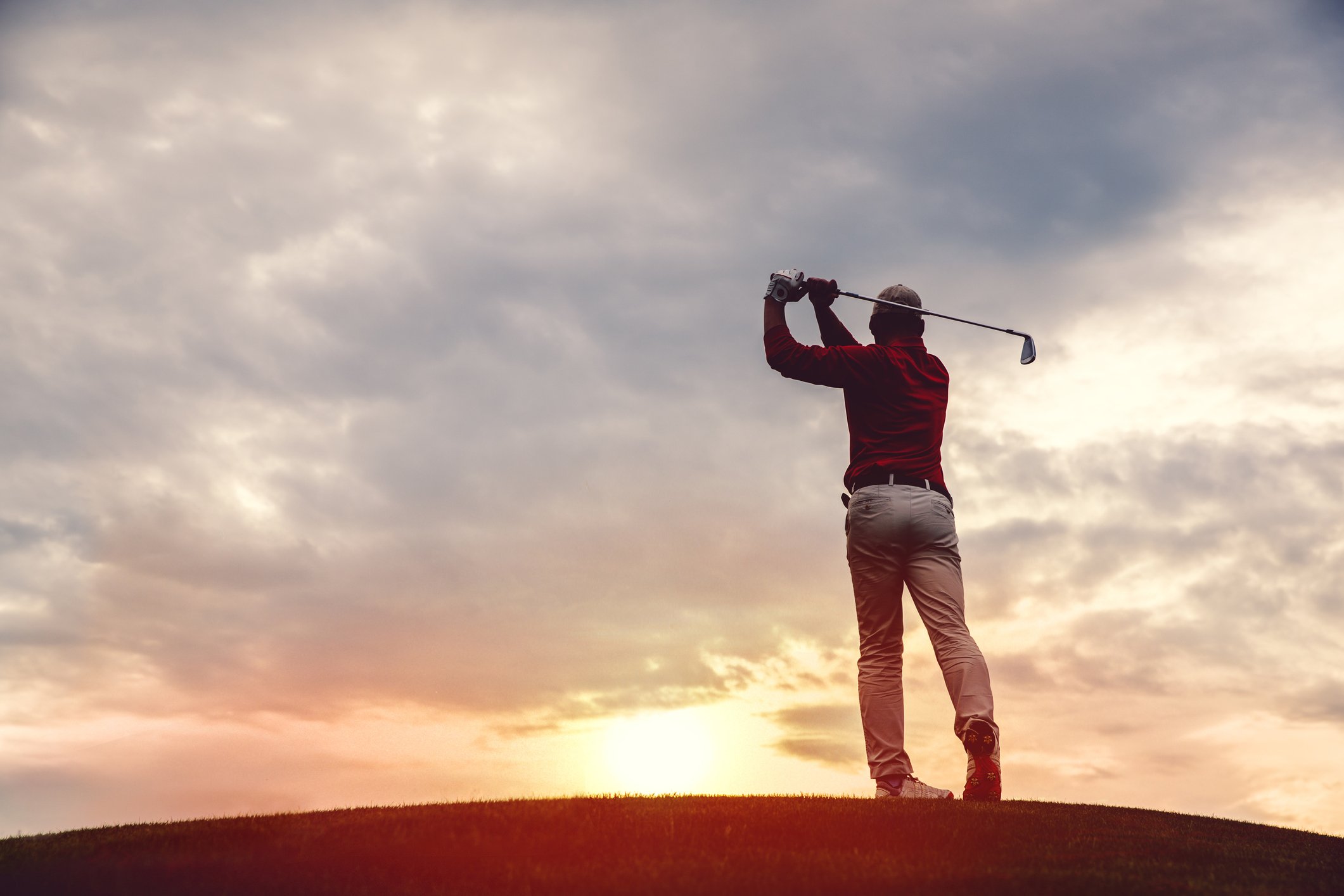 Silhouette of a man golfing at dusk.