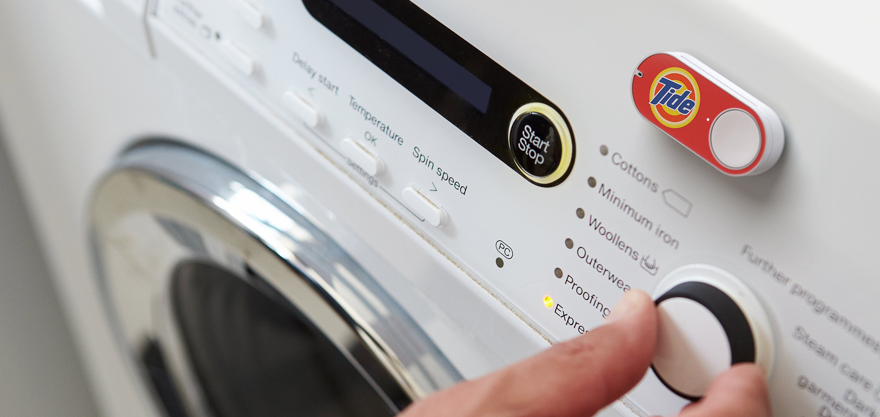 An Amazon Dash button for Tide sits on a washing machine.
