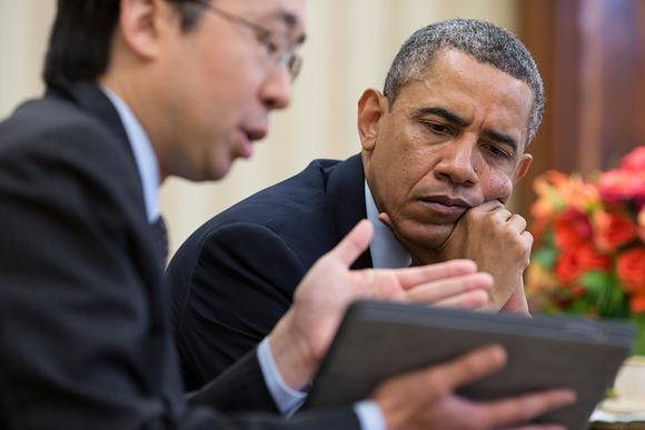 Former President Barack Obama reviewing Obamacare enrollment data on a tablet. 