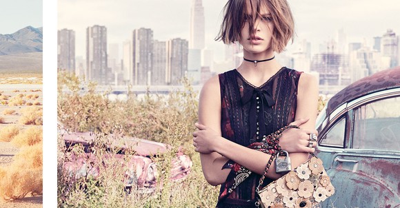 A woman holds a Coach handbag while leaning against a retro car with a cityscape in the background.