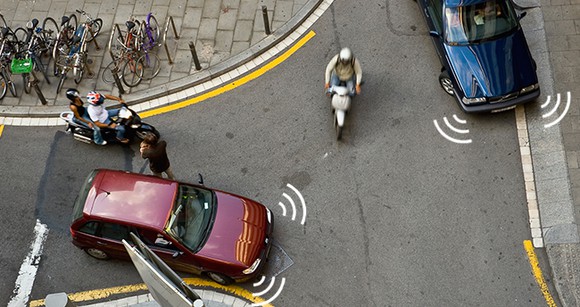 Cars and motorcycles navigate an intersection, with illustrations suggesting image sensors on the cars.