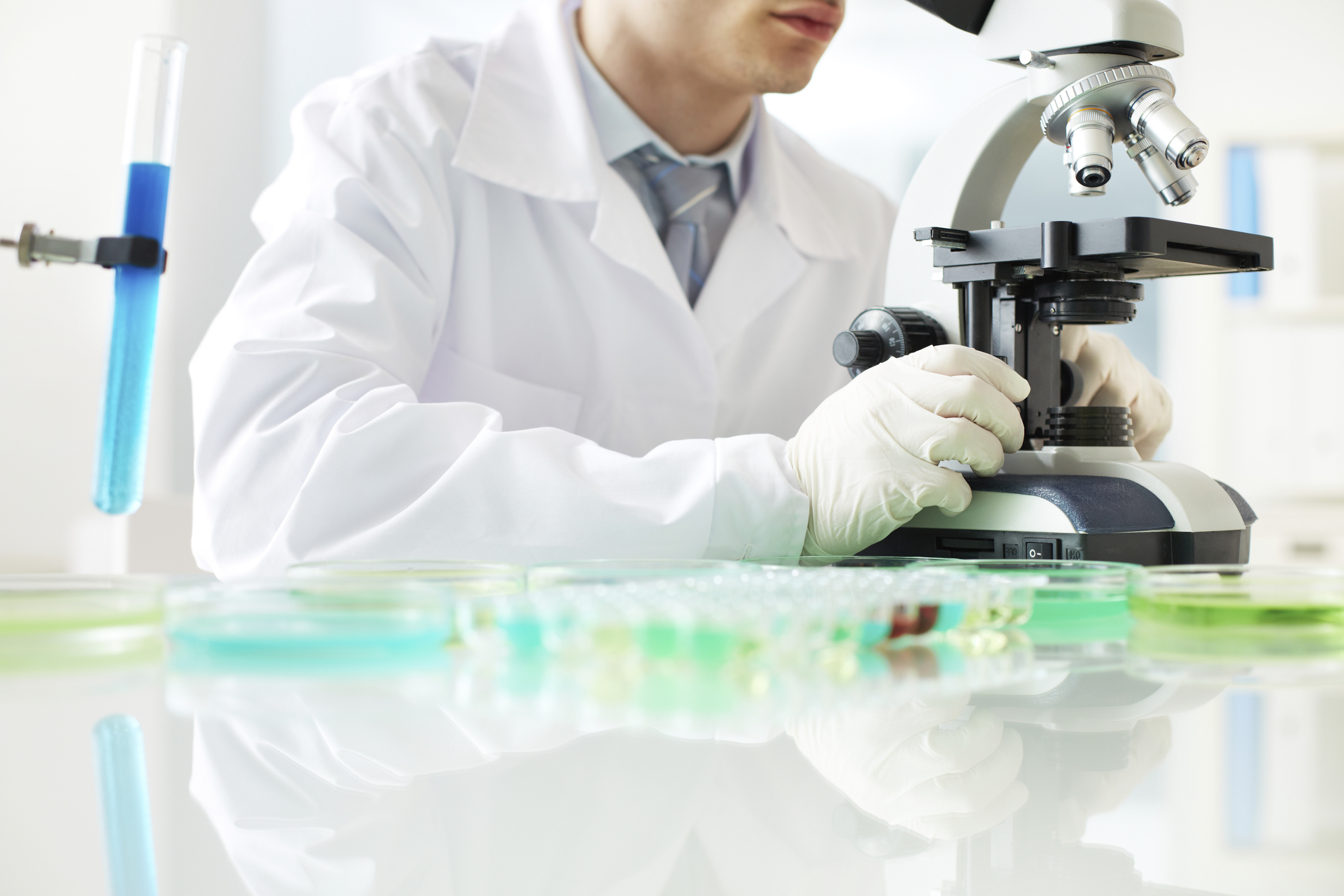 A biotech lab researcher using a microscope. 