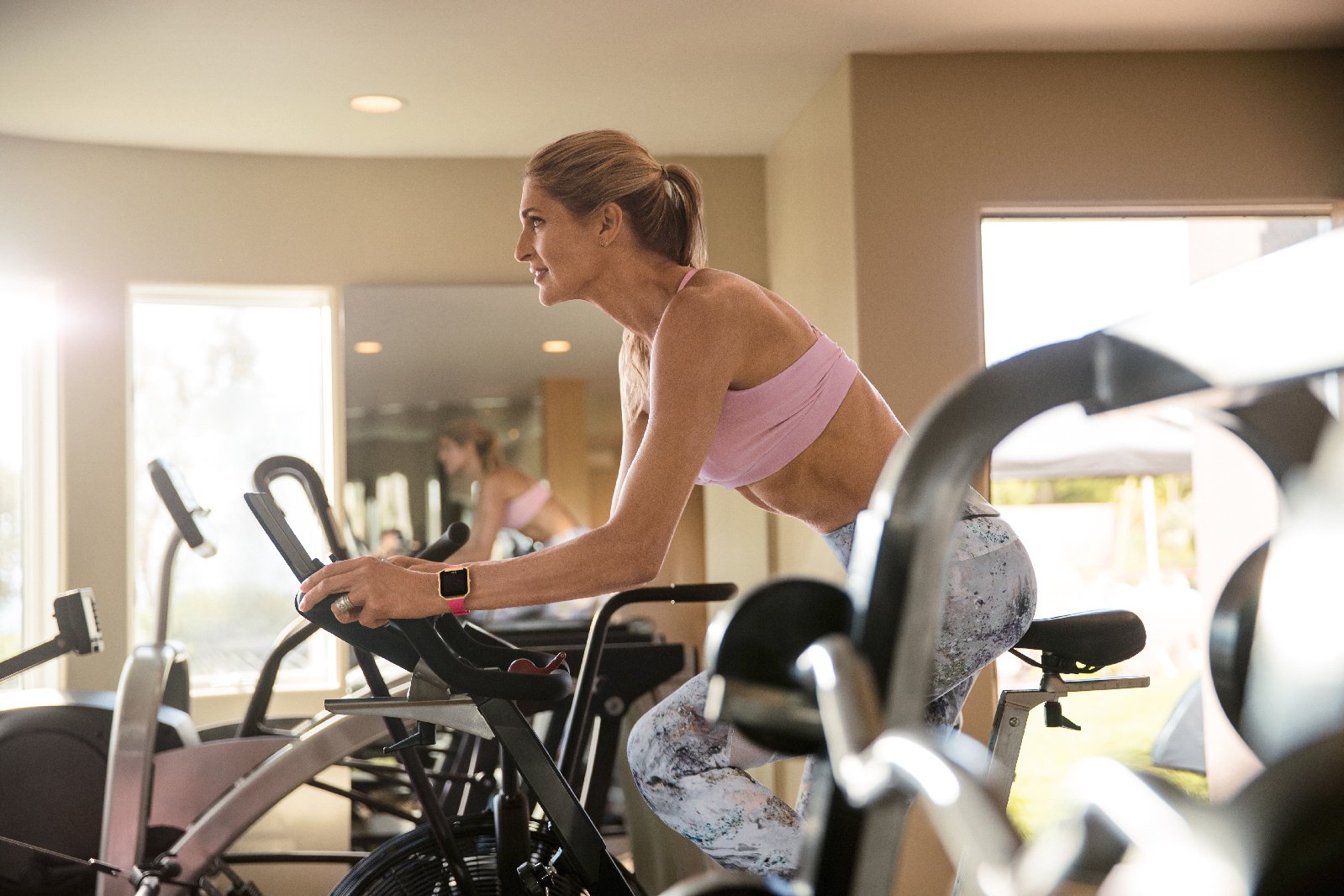 Gabby Reece sports a Fitbit while using a stationary bicycle.