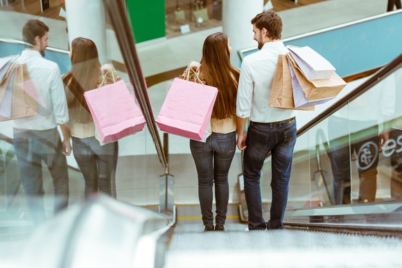 Couple going down an escalator with shopping bags.