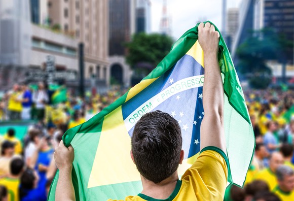 Man in Brazilian green and gold, holding the Brazilian flag