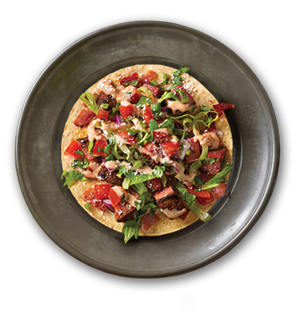 A picture of Knockout Tacos from Qdoba's menu, a taco loaded with chicken, salsa, and queso sauce.