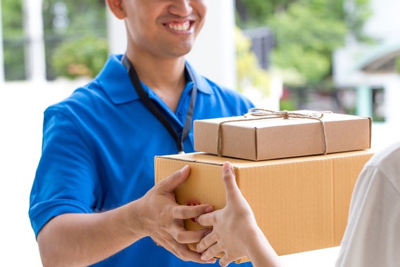 A person delivers a box of items to a customer's home.