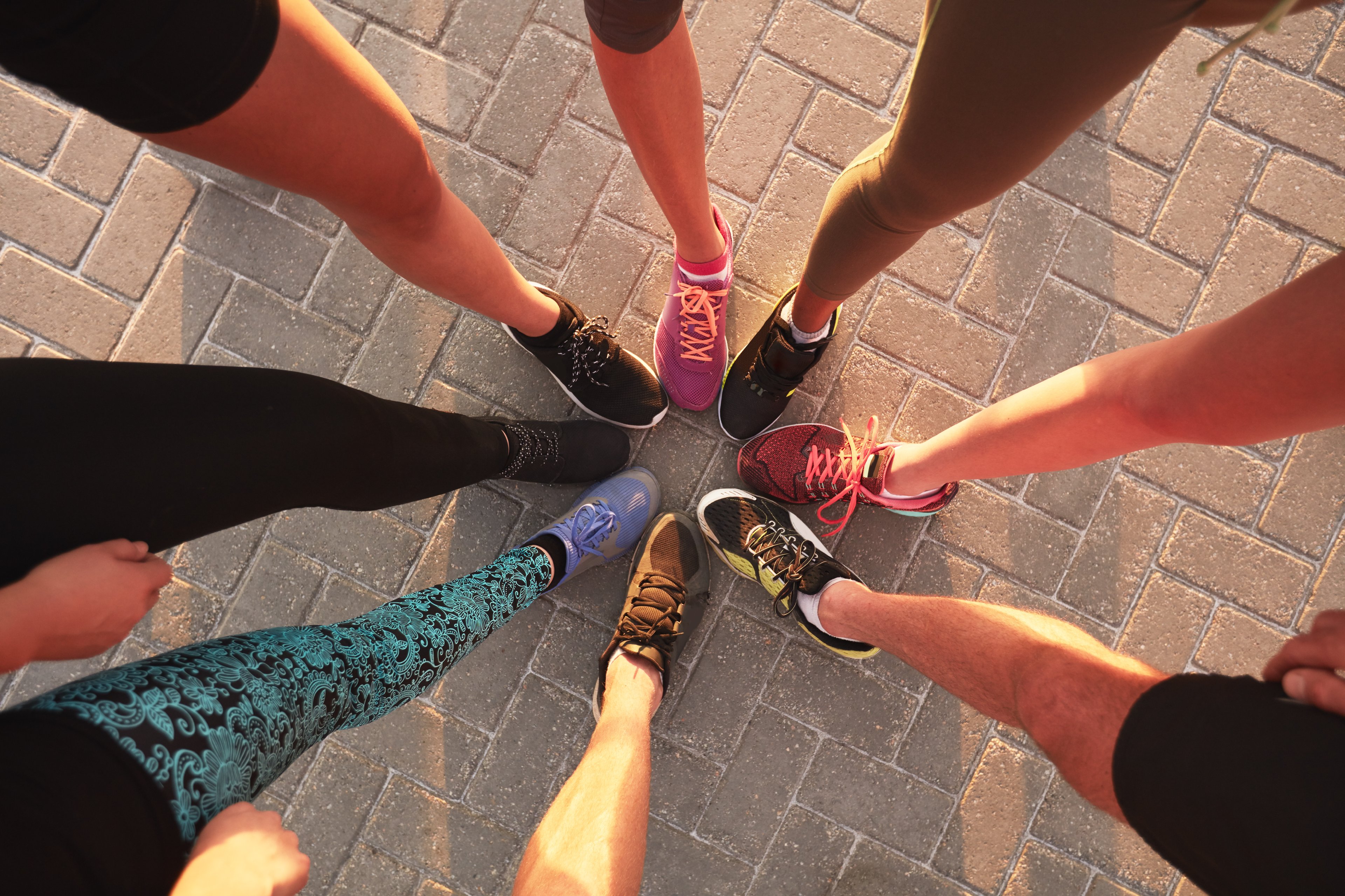 A group of runners' feet meeting in the center of a circle