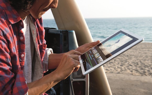 A person uses an iPad Pro on the beach.
