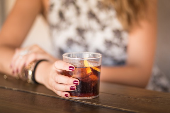 A woman holds a glass of soda.