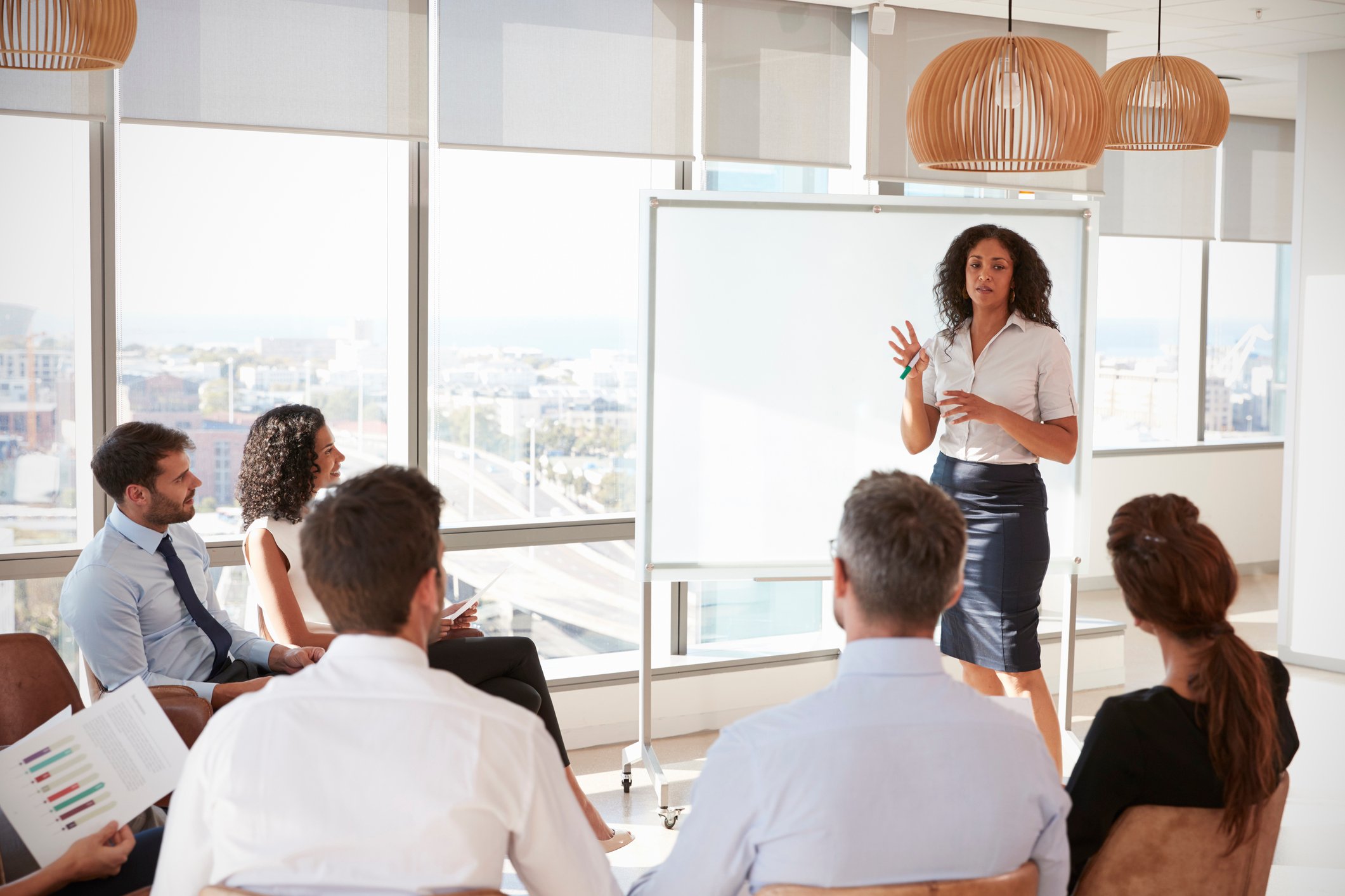 A consultant stands before a whiteboard, delivering a presentation.