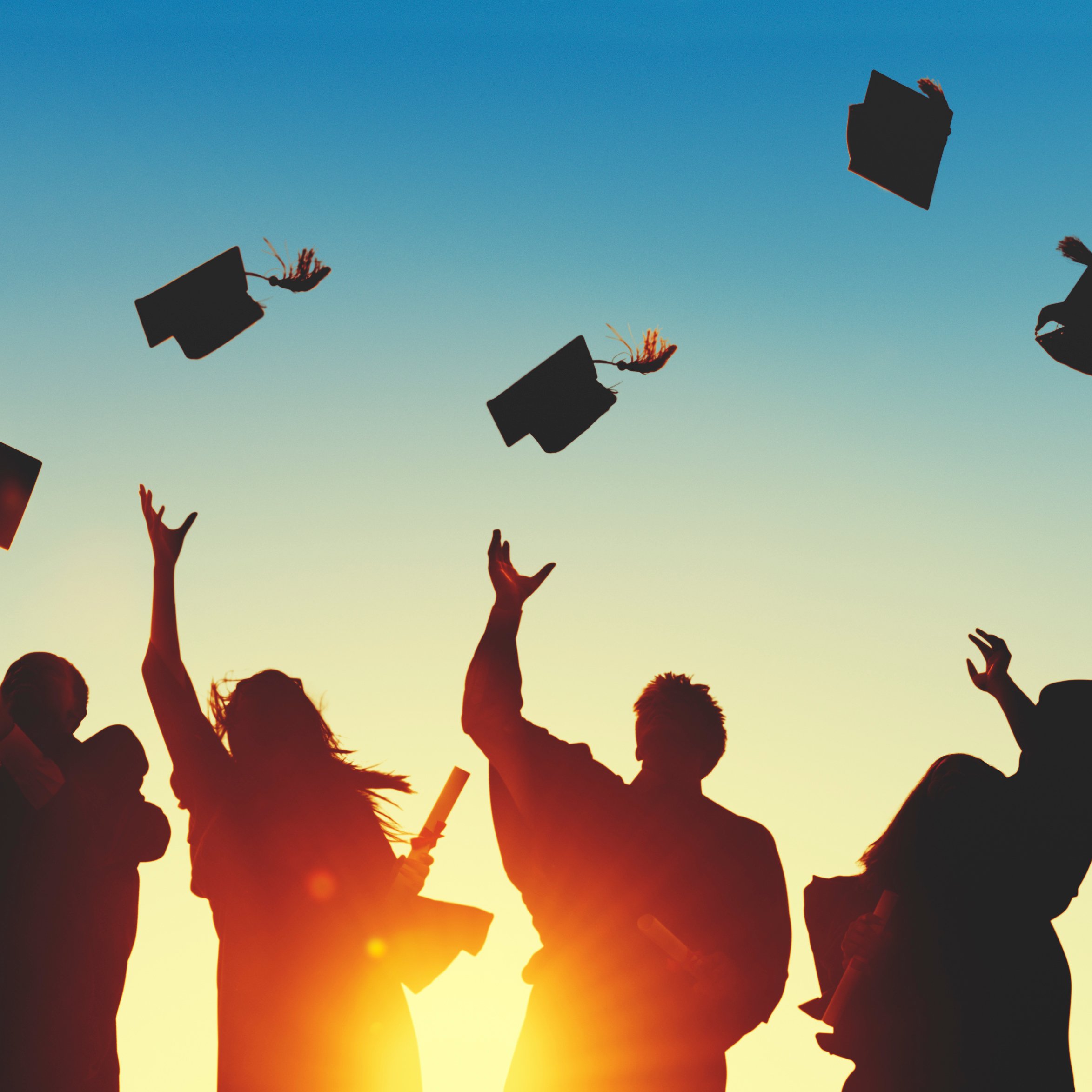 College graduates throw their caps in the air.