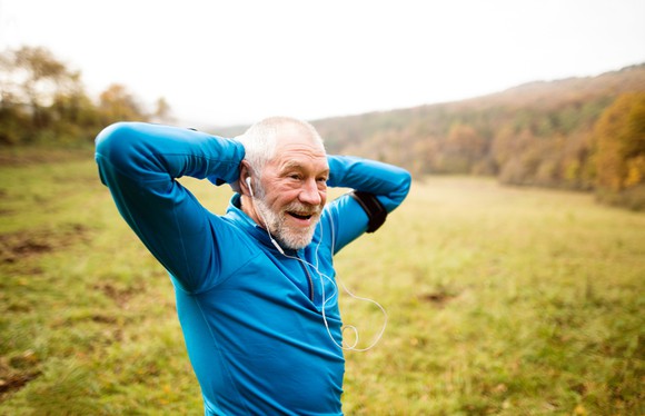 A senior citizen taking a break from a run in an open field.