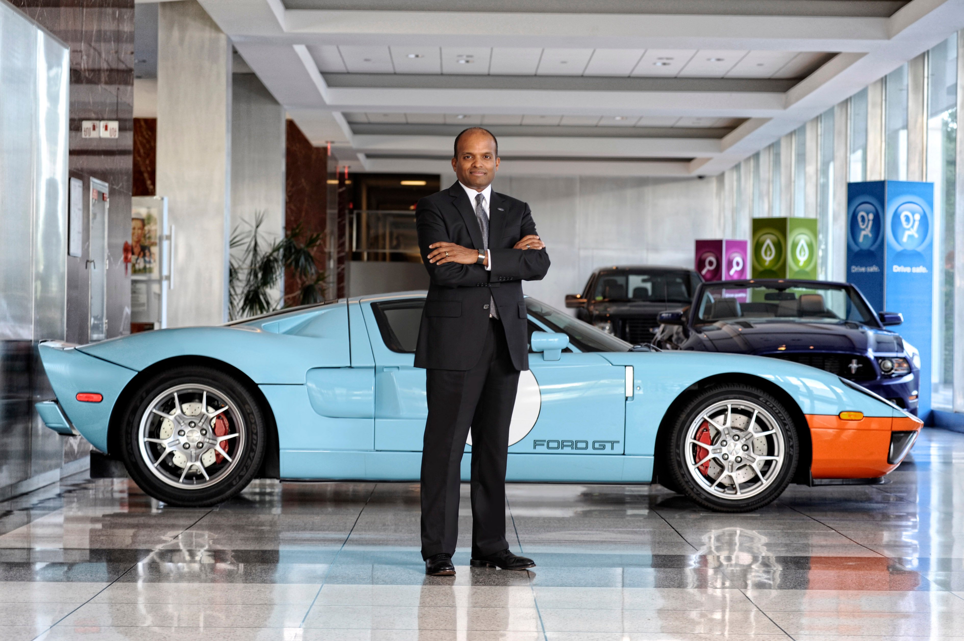 Nair is standing in front of a Ford GT sports car. 