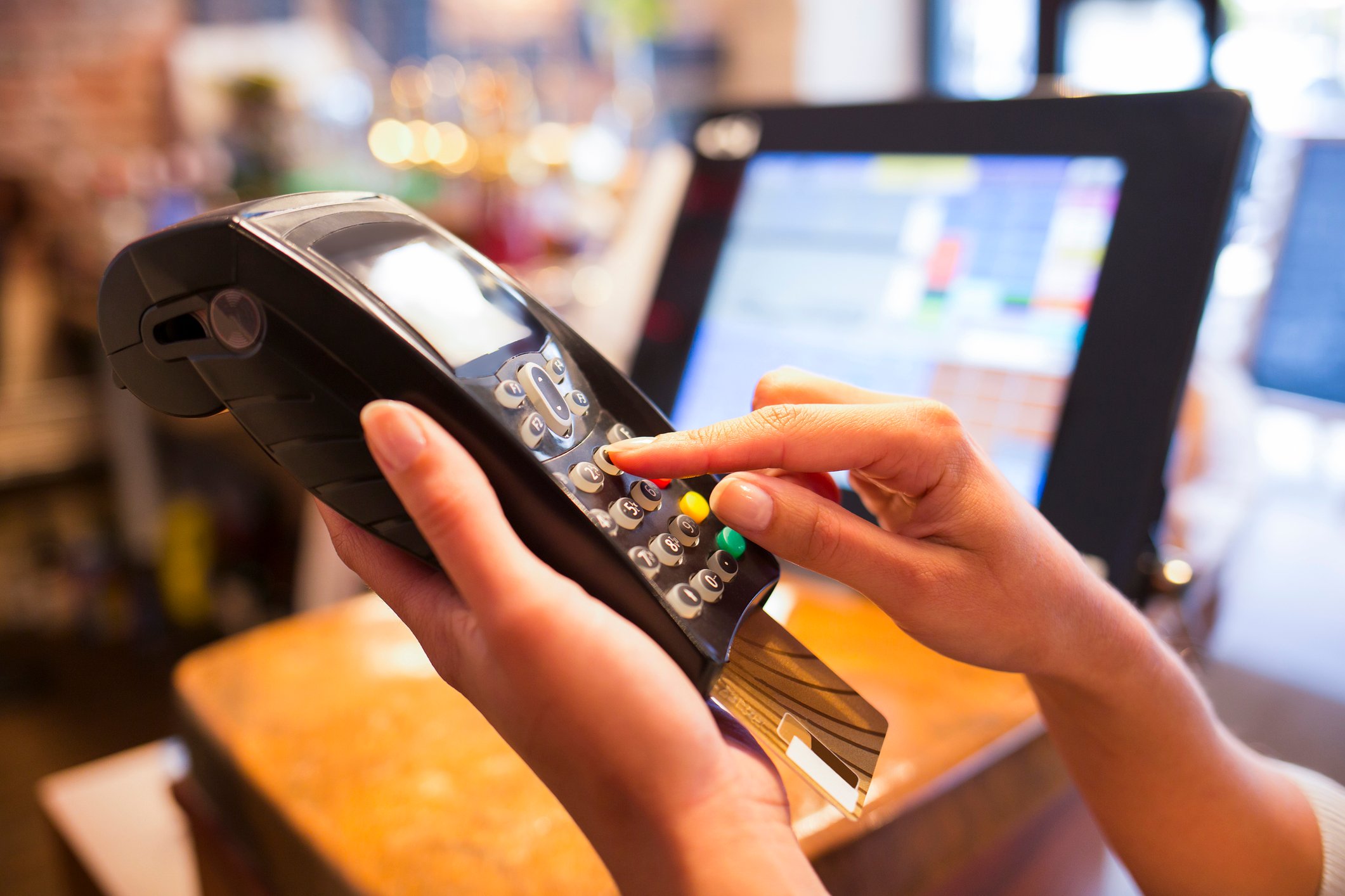 Cashier ringing up a credit card transaction on a handheld credit processing device.