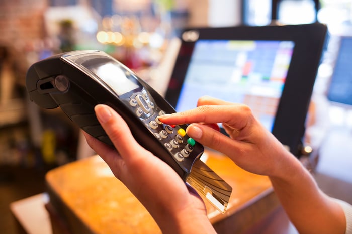 Cashier ringing up a credit card transaction on a handheld credit processing device.