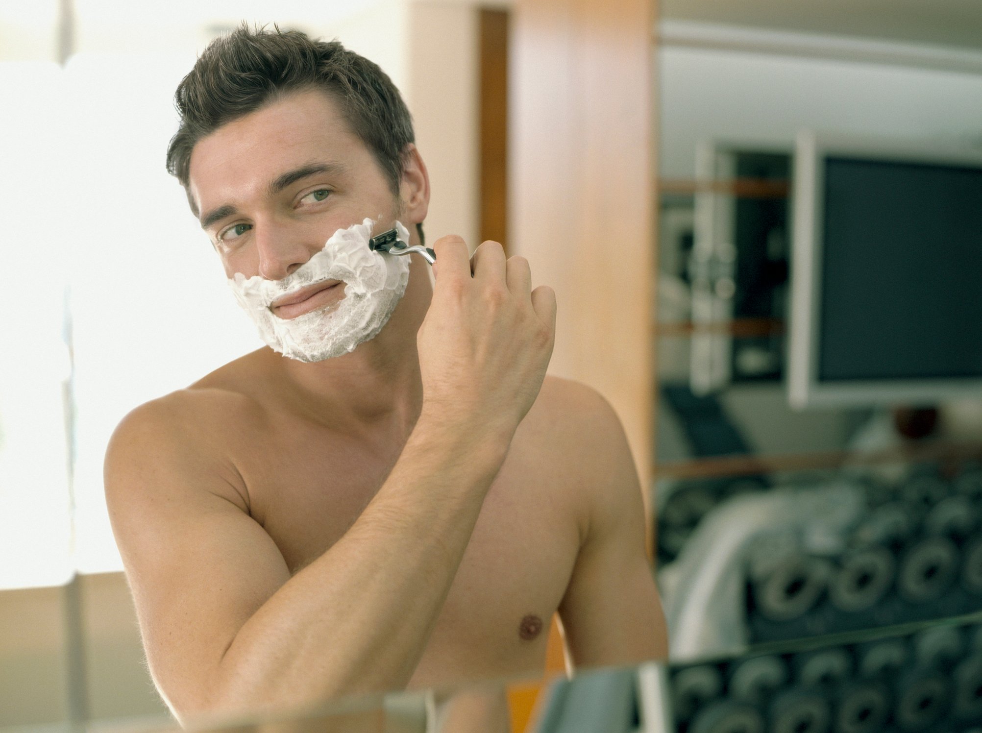 A man shaving in a mirror.