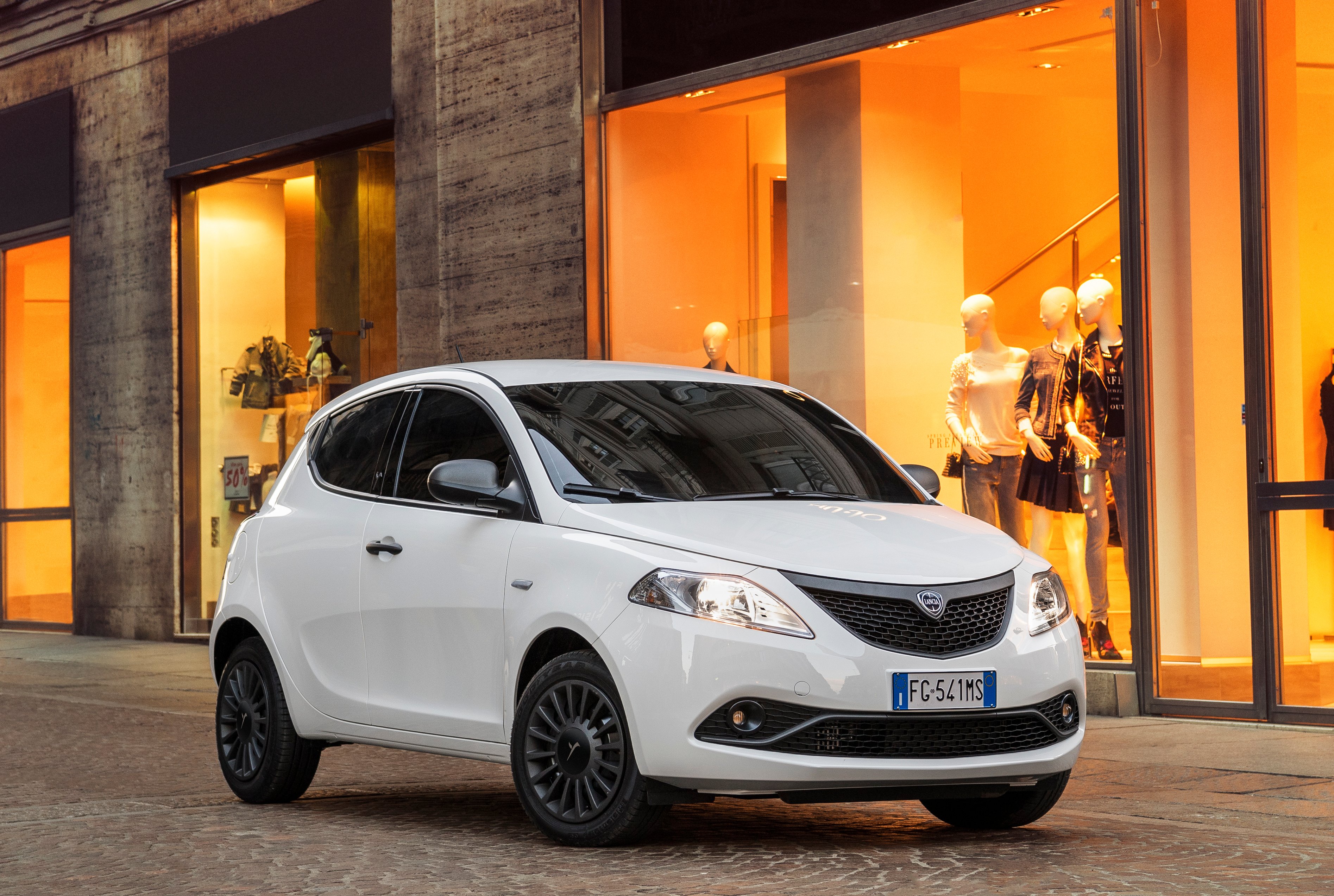 A white Lancia Ypsilon hatchback on a city street. 