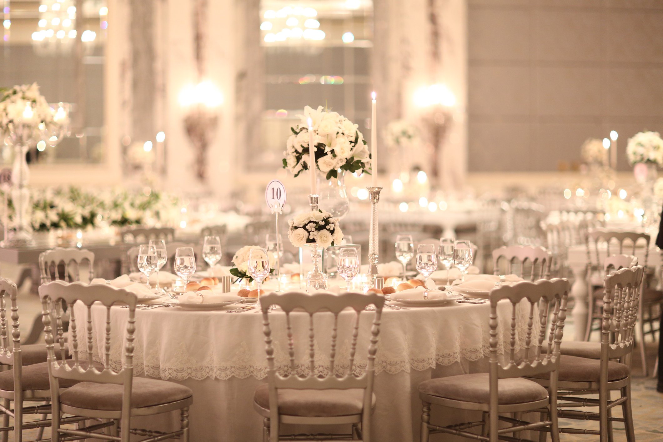 Luxurious white wedding reception tables with candles and floral centerpieces