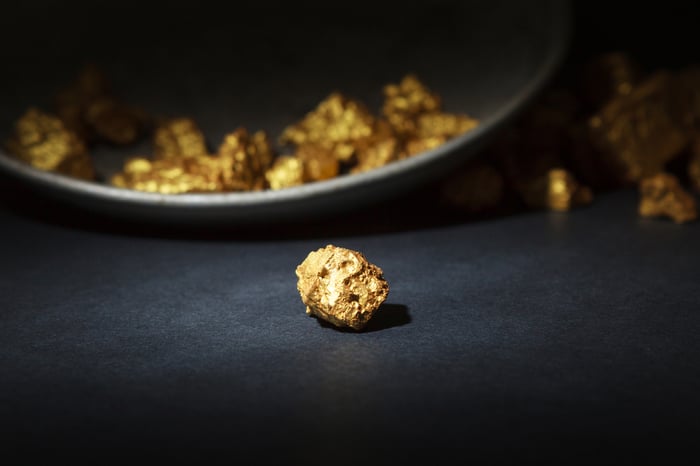 Gold nuggets sitting on a black table.