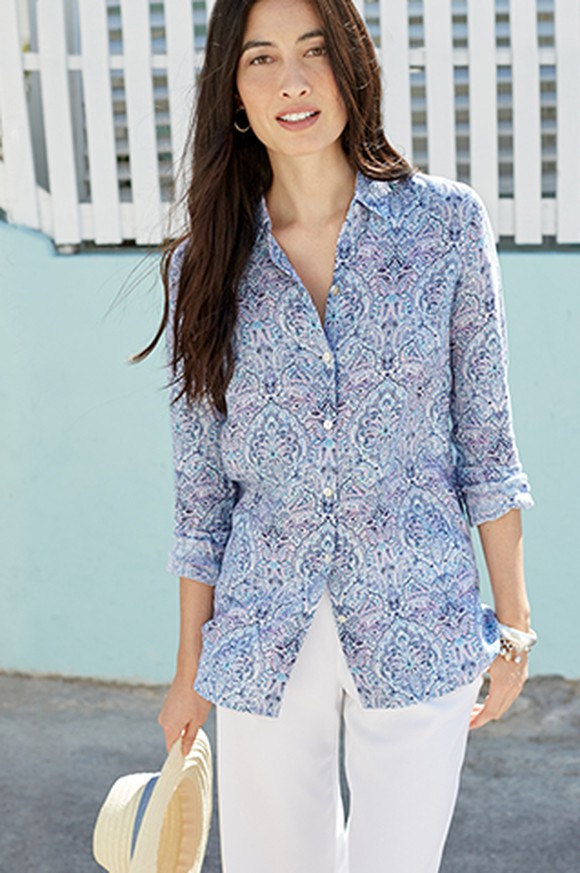 A J. Jill Model wearing white pants and a blue top while holding a straw hat.