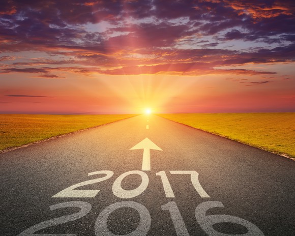The numbers "2016" and "2017" with an up arrow above them on an empty road leading to a shining sun