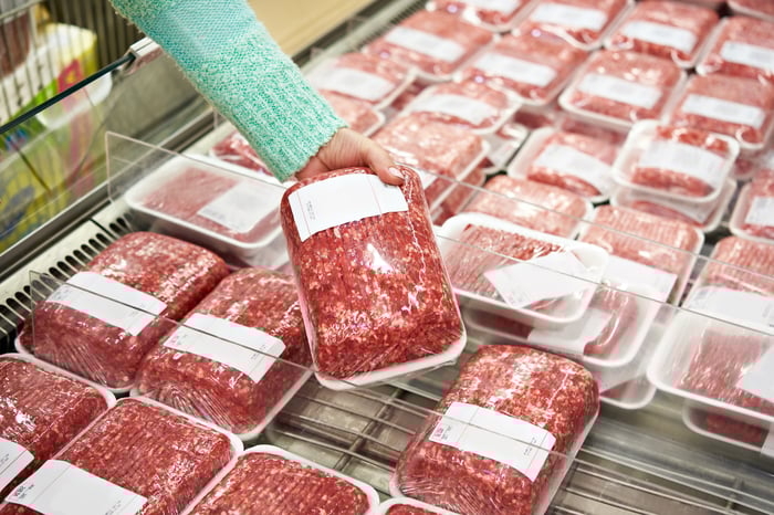 Woman selecting package of ground beef.