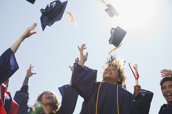 College graduates throw their caps into the air at a graduation ceremony.