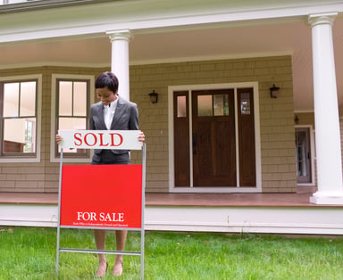 Real Estate Woman Putting Up Sold Sign for Home