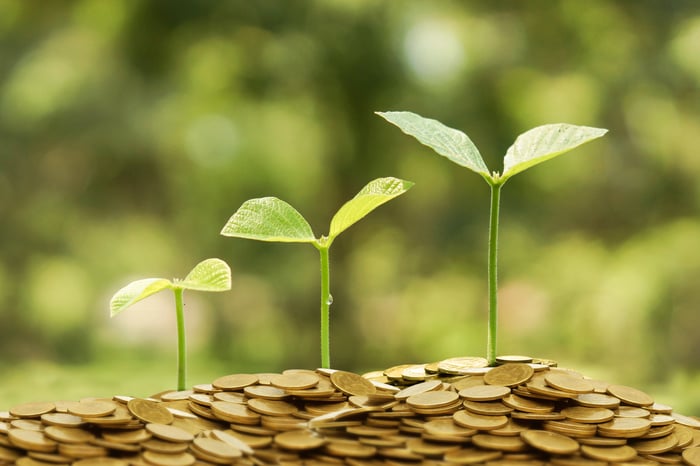 Three plants sprout from a stack of coins, each successively taller.