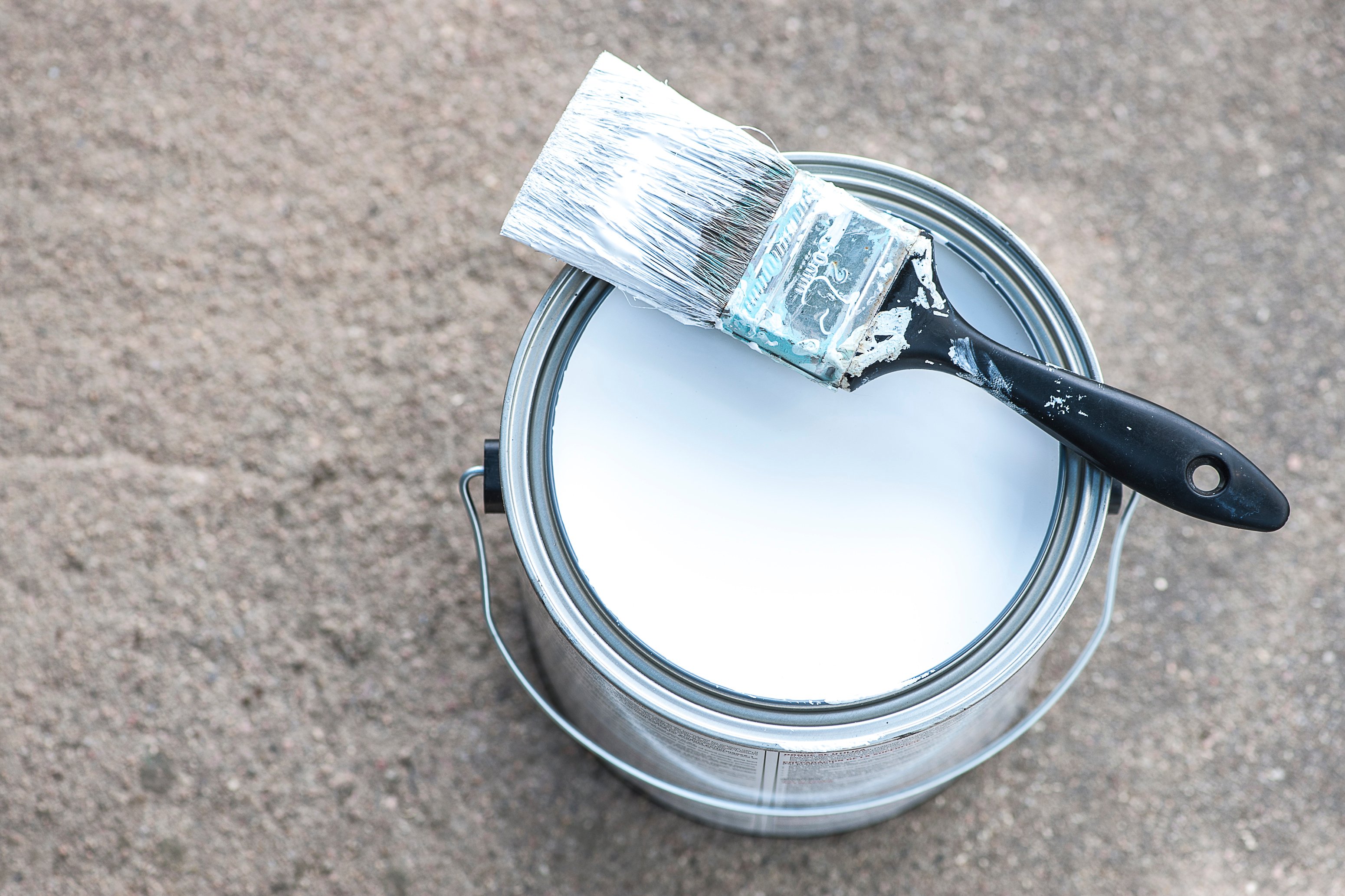 Can of white paint with brush