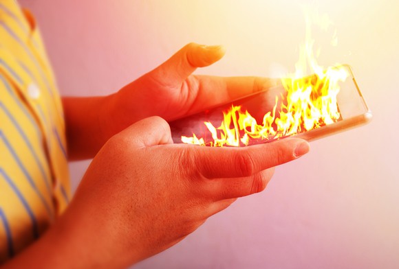 Person holding a smartphone on fire