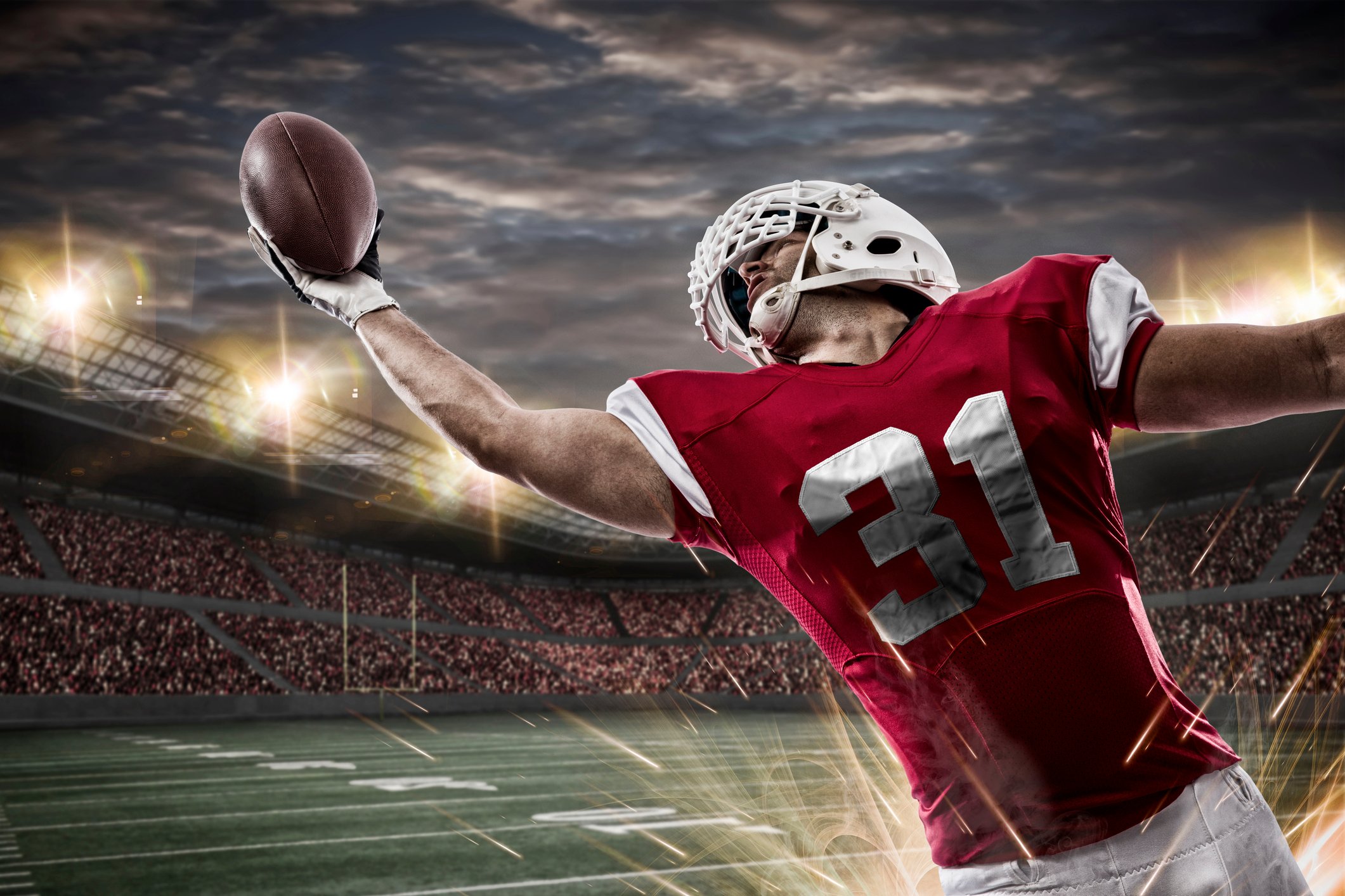 A football player stretches his arm to catch the ball.