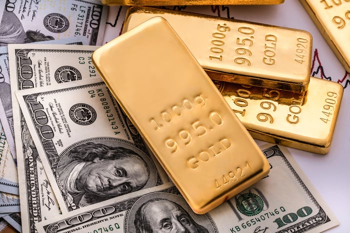 Gold bars rest atop one-hundred-dollar bills.