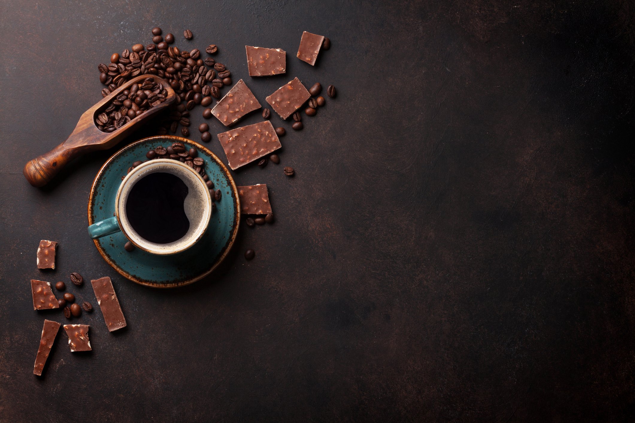 Overhead view of a coffee cup with coffee beans around the table.