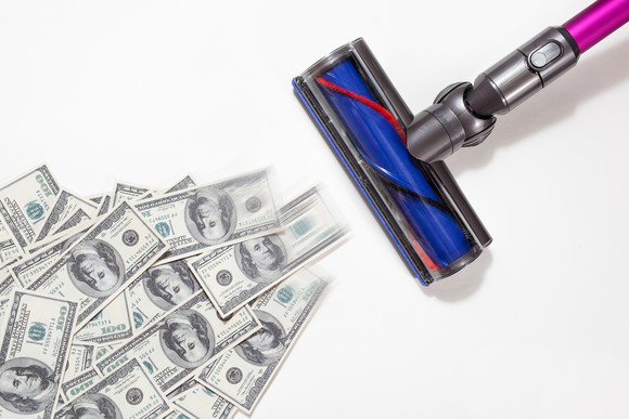 A vacuum sucking up dollar bills