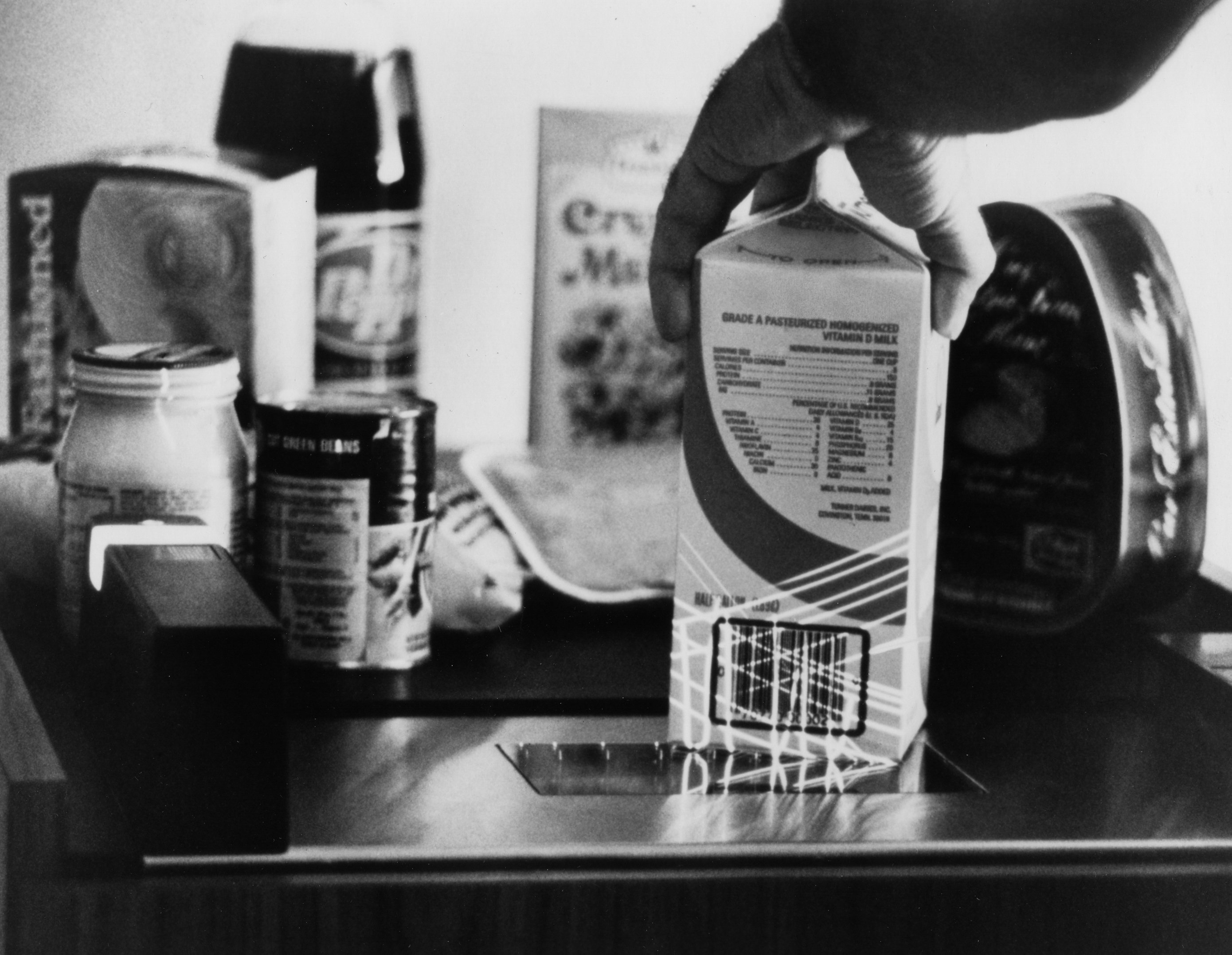 A black and white picture of a milk carton being scanned.