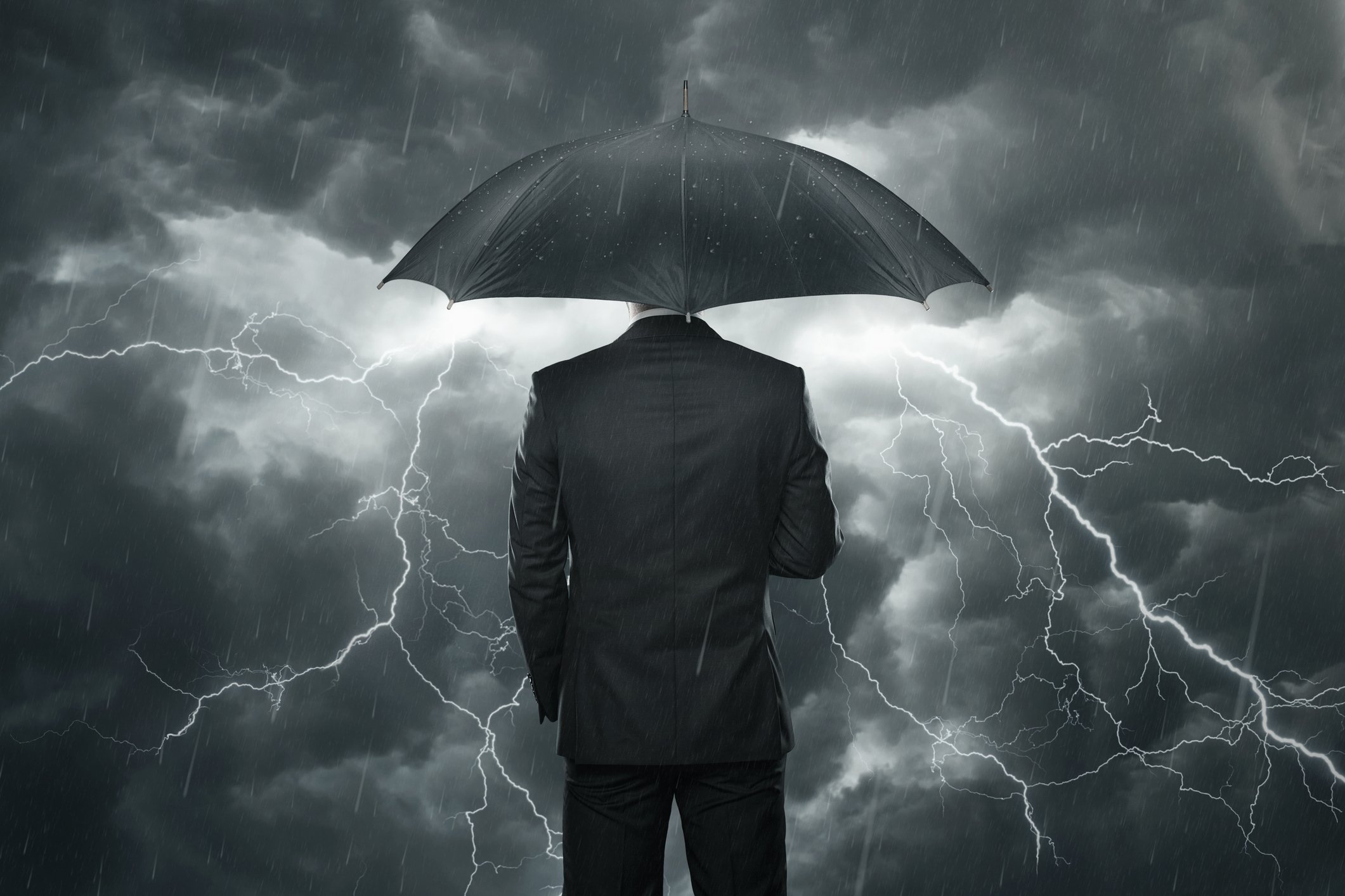 Businessman staying dry in a storm.