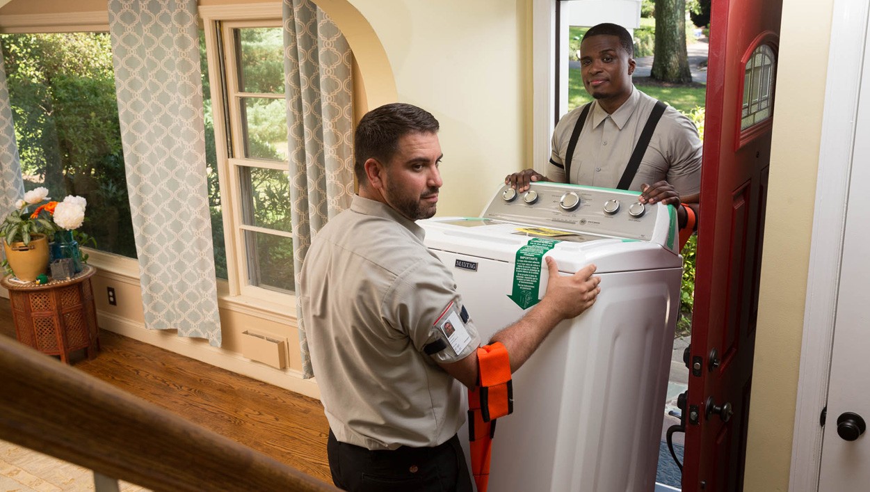 Two men hauling a large home appliance.