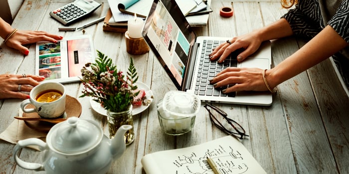 Hands on laptop and mobile devices on a rustic desk, representation of online shopping.