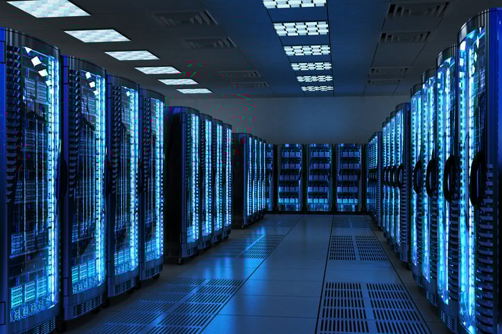 Servers glow with a low blue light in rows inside a server data center.