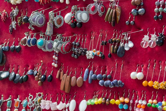 Multiple pairs of earrings are pinned to a red board.
