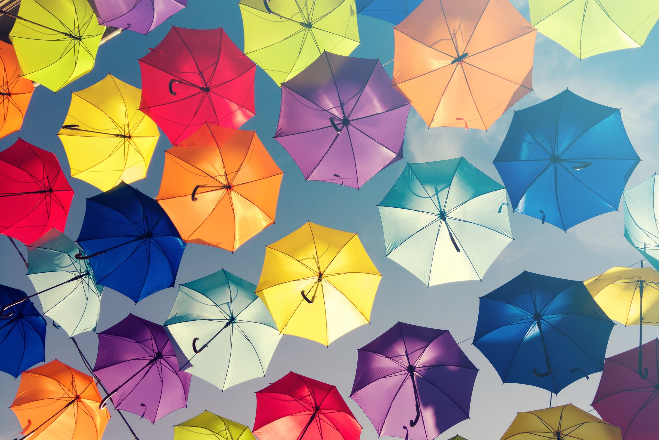 Several colorful umbrellas are opened, with a blue sky above them.