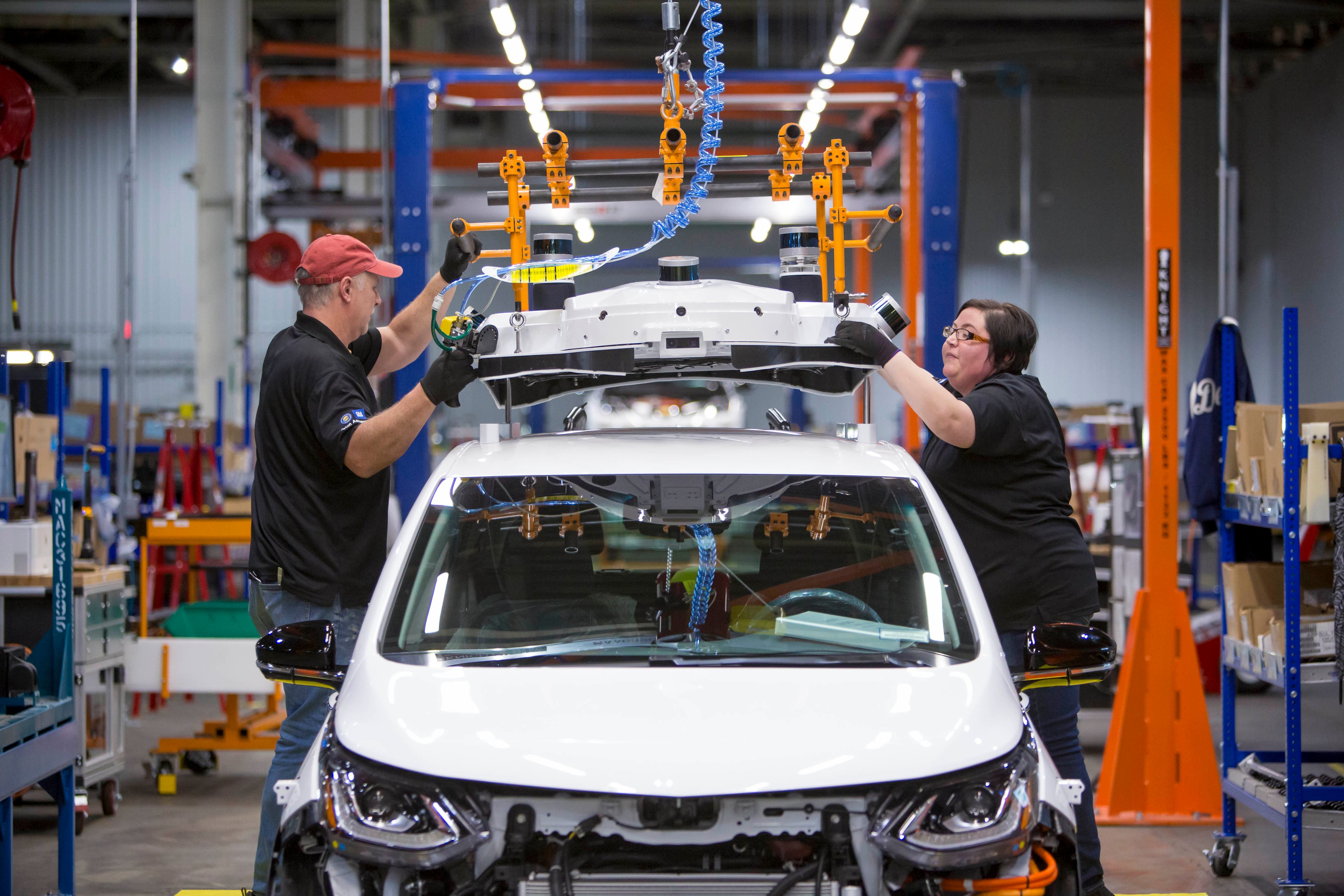Workers install self-driving hardware on Chevrolet Bolt EVs.