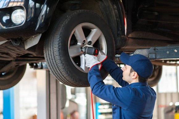 A mechanic replacing a car wheel.