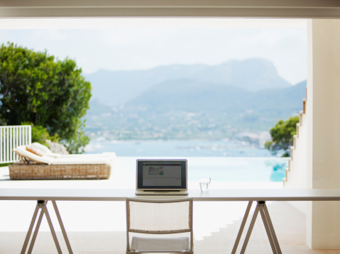A laptop on a table with a background view of a waterfront