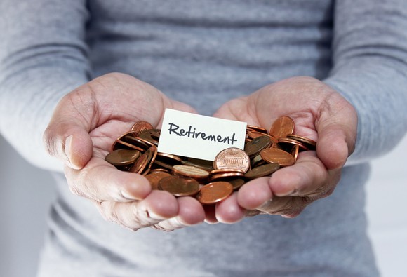 A man's hands holding coins and a paper with retirement written on it.